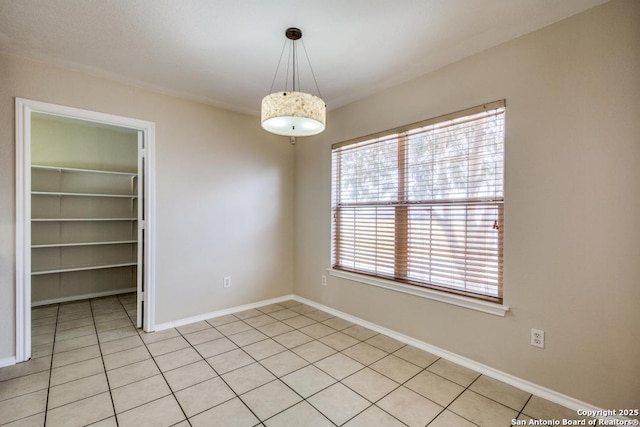 unfurnished room with light tile patterned flooring and baseboards