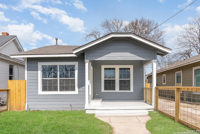 view of front of property featuring roof with shingles, a front yard, and fence