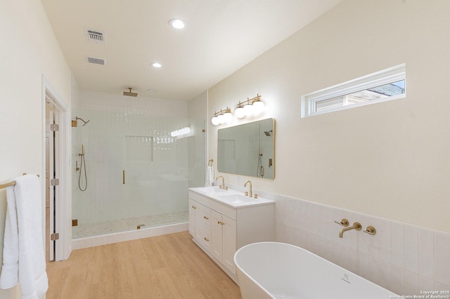 bathroom with a soaking tub, visible vents, a stall shower, vanity, and wood finished floors