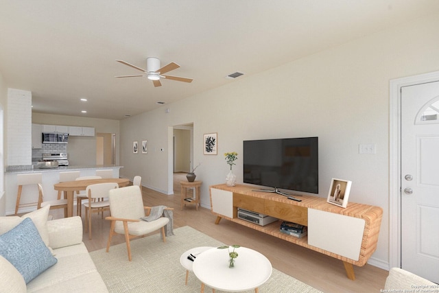 living room with a ceiling fan, light wood-type flooring, visible vents, and baseboards