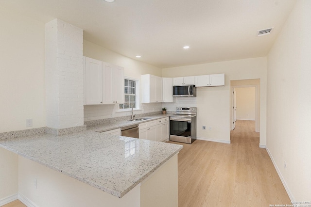 kitchen featuring visible vents, decorative backsplash, appliances with stainless steel finishes, a peninsula, and white cabinetry