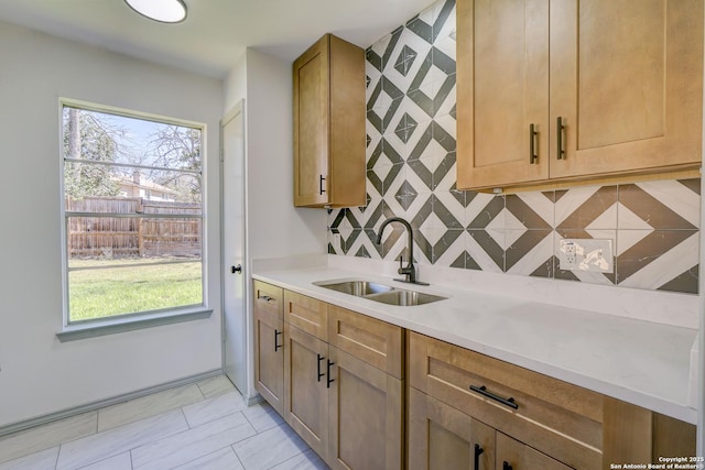 kitchen featuring a healthy amount of sunlight, backsplash, a sink, and light countertops