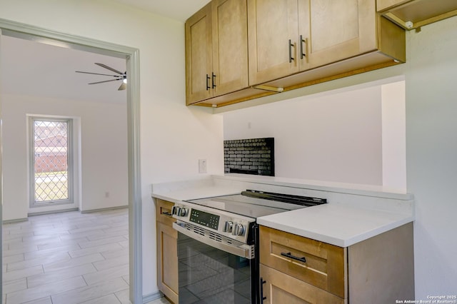 kitchen with a ceiling fan, light countertops, electric range, and baseboards