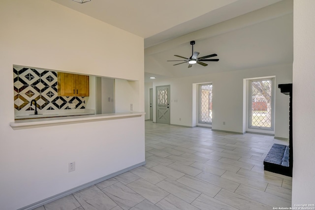 empty room with high vaulted ceiling, ceiling fan, and baseboards