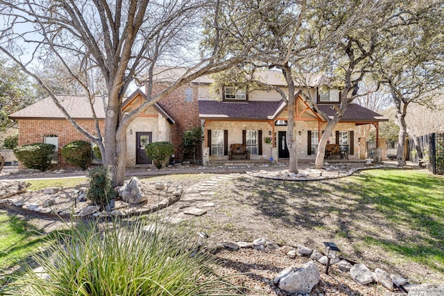 view of front facade with a front yard, stone siding, roof with shingles, and a chimney