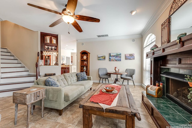 living area featuring visible vents, baseboards, stairs, ornamental molding, and a tiled fireplace