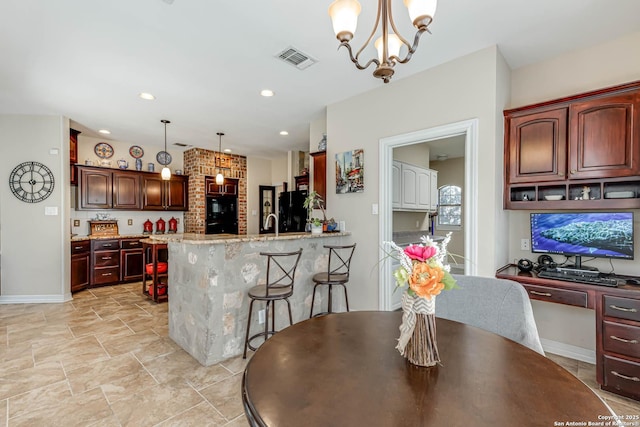 kitchen with visible vents, built in study area, a kitchen breakfast bar, a peninsula, and black appliances