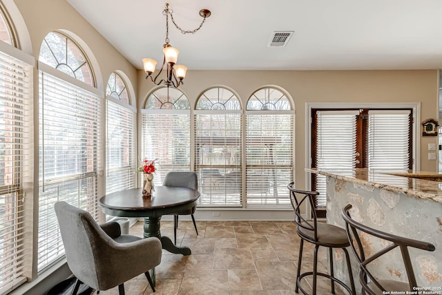 dining room featuring a chandelier, stone finish floor, and visible vents