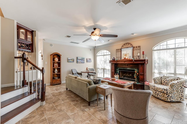 living area with crown molding, visible vents, a fireplace, and stairs