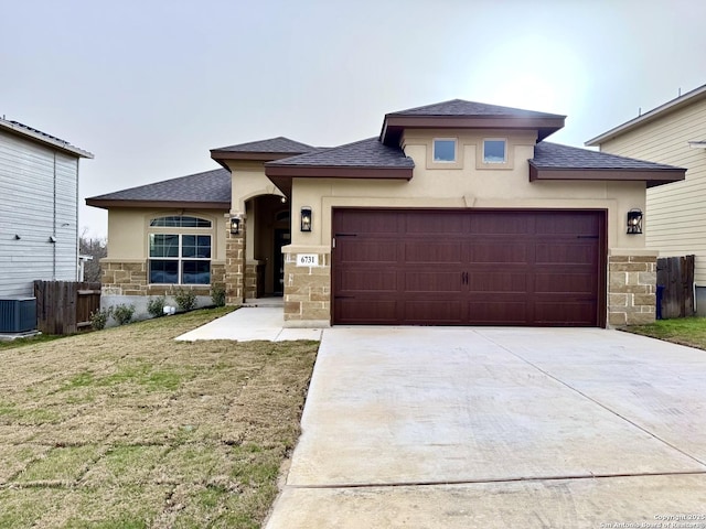 prairie-style home with a garage, stone siding, driveway, and stucco siding