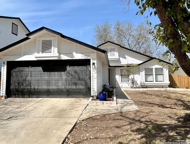 view of front facade with driveway, an attached garage, and fence