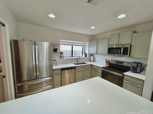 kitchen featuring stainless steel appliances, a sink, visible vents, light countertops, and tasteful backsplash