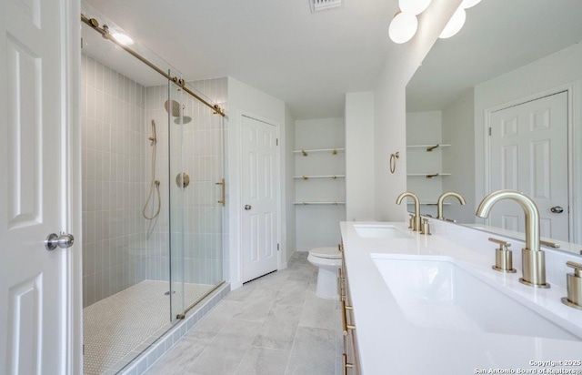 bathroom featuring double vanity, a stall shower, toilet, and a sink