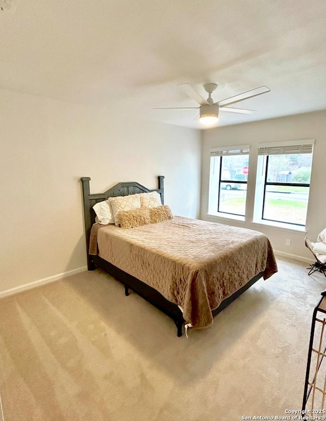 bedroom with a ceiling fan, light colored carpet, and baseboards