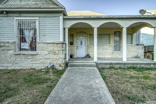 entrance to property with a porch and stone siding