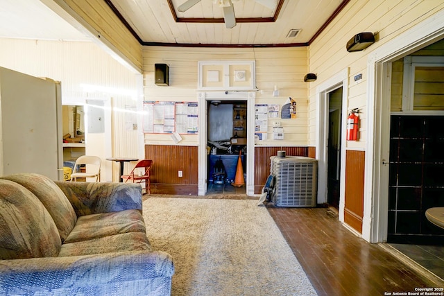 living room with wood walls, visible vents, a ceiling fan, and wood finished floors