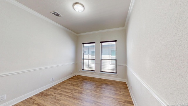 unfurnished room with baseboards, light wood-style flooring, visible vents, and crown molding