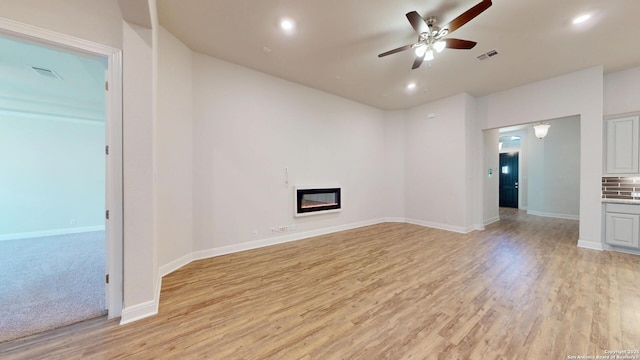 unfurnished living room with ceiling fan, light wood finished floors, a glass covered fireplace, and recessed lighting