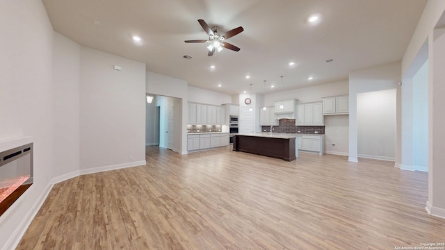 unfurnished living room featuring recessed lighting, baseboards, ceiling fan, and light wood finished floors