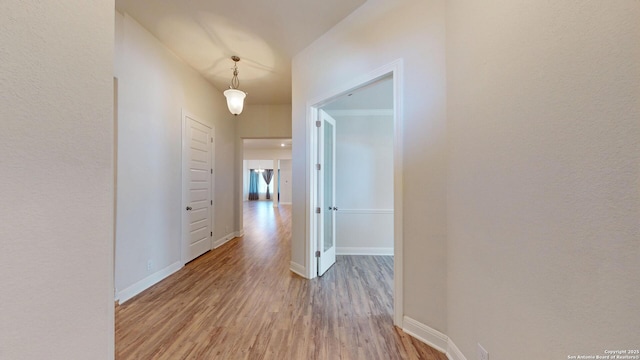 hall featuring light wood-style floors and baseboards