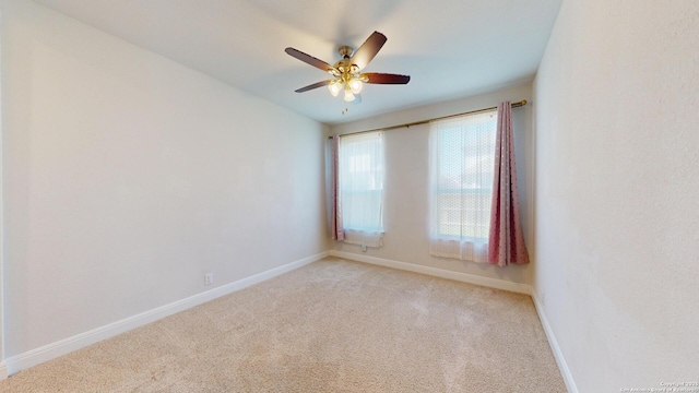 empty room with baseboards, ceiling fan, and light colored carpet