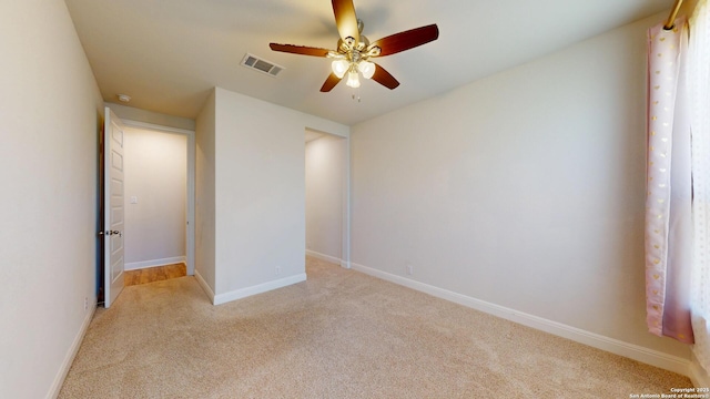 empty room with light carpet, baseboards, visible vents, and ceiling fan