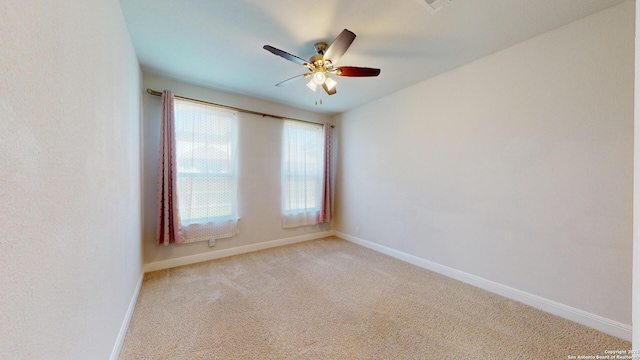 spare room featuring baseboards, a ceiling fan, and light colored carpet