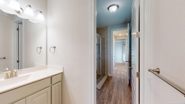 full bathroom with a shower stall, wood finished floors, and vanity