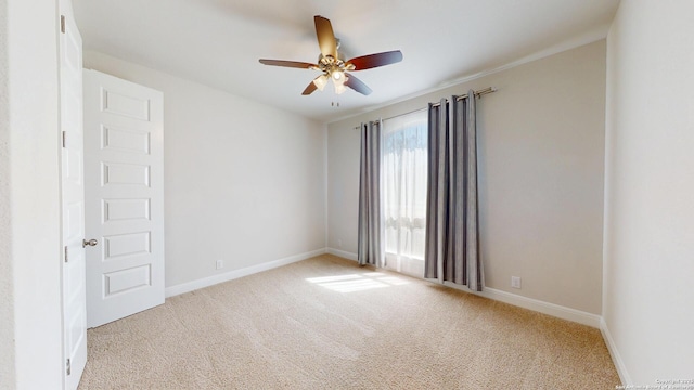 carpeted empty room featuring baseboards and a ceiling fan