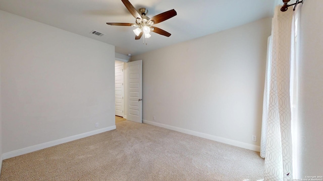 carpeted empty room featuring ceiling fan, visible vents, and baseboards