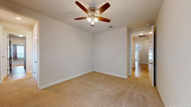 unfurnished room with baseboards, ceiling fan, visible vents, and light colored carpet