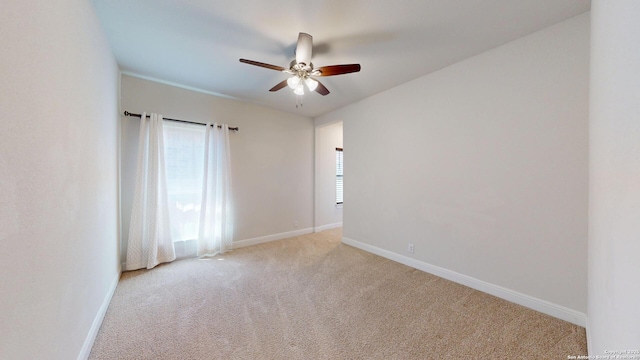 spare room with light carpet, ceiling fan, and baseboards