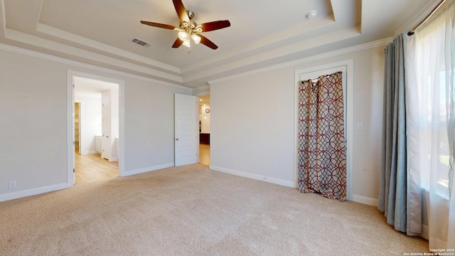 spare room featuring visible vents, a raised ceiling, and light colored carpet