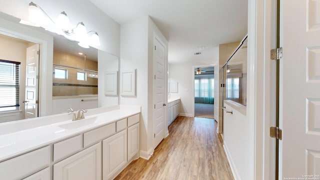 full bathroom with baseboards, a tile shower, wood finished floors, and vanity