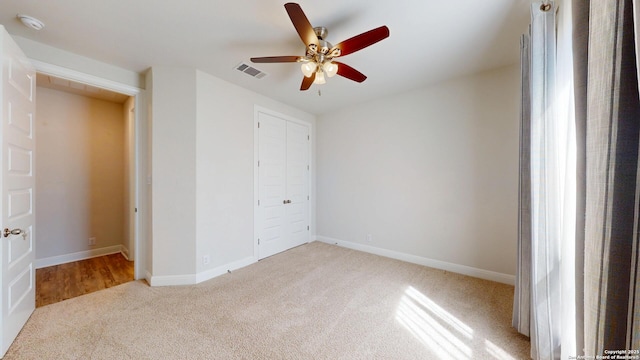 unfurnished bedroom featuring ceiling fan, carpet flooring, visible vents, baseboards, and a closet