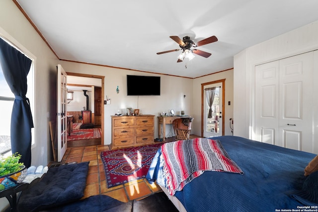 tiled bedroom with a ceiling fan, ornamental molding, and a closet