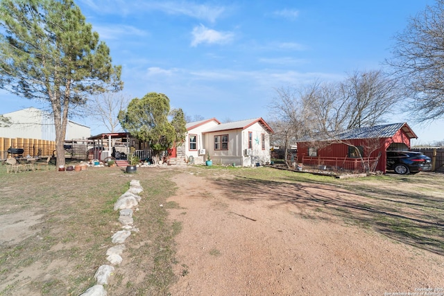 view of front of property featuring a pole building, fence, metal roof, and an outdoor structure