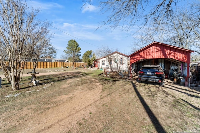 view of front of home featuring dirt driveway and fence