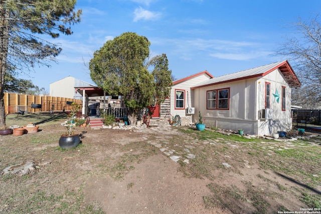 view of front of property featuring metal roof and fence