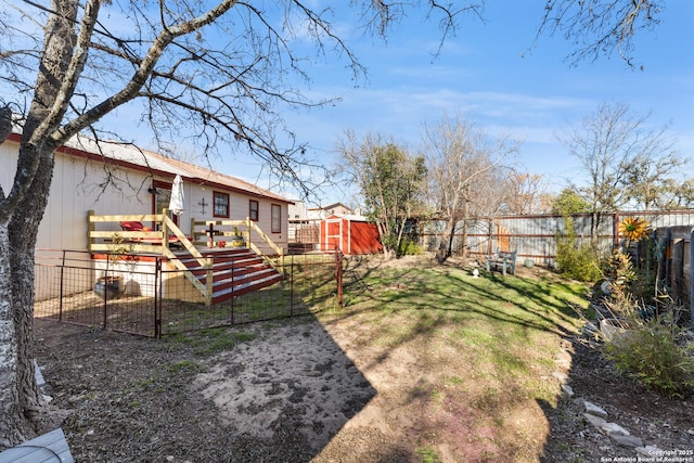 view of yard featuring an outbuilding, a gate, a fenced backyard, and a storage unit