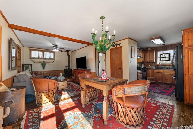 dining space with wainscoting, plenty of natural light, wooden walls, and ceiling fan with notable chandelier