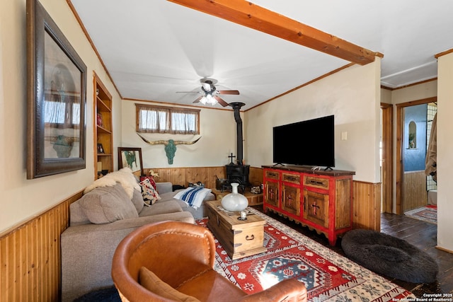 living area with a wood stove, a wainscoted wall, crown molding, and wood walls