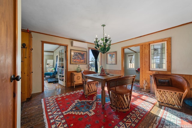 dining room with a wall unit AC, an inviting chandelier, crown molding, and hardwood / wood-style floors