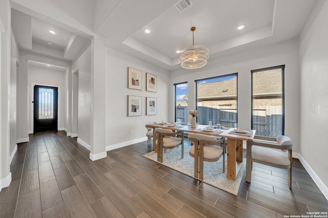 dining area with a healthy amount of sunlight, wood tiled floor, visible vents, and a tray ceiling