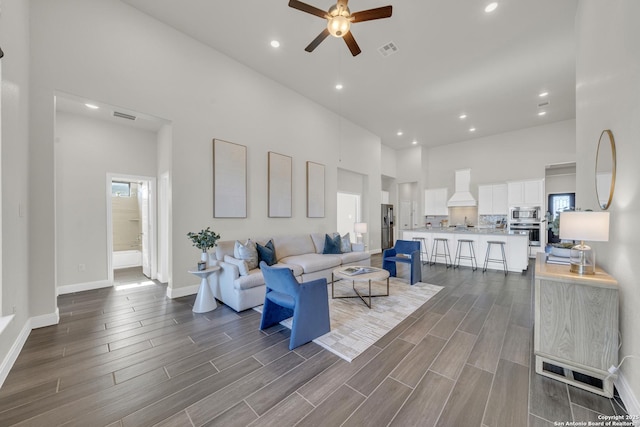 living room with wood tiled floor, visible vents, and a towering ceiling