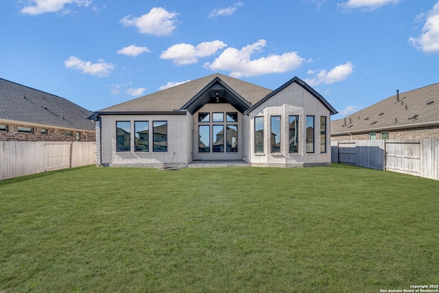 back of property with a yard, brick siding, and a fenced backyard