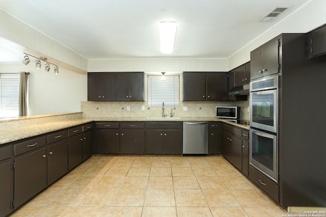 kitchen with visible vents, decorative backsplash, appliances with stainless steel finishes, a sink, and under cabinet range hood