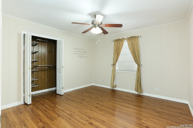 spare room featuring baseboards, ceiling fan, ornamental molding, and wood finished floors