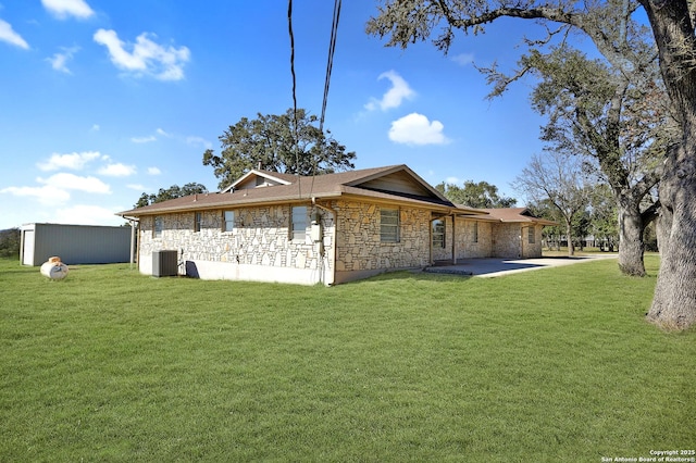 back of house with stone siding, a lawn, a patio, and central air condition unit