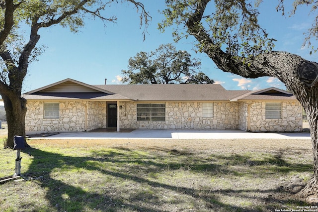 ranch-style home featuring stone siding and a front yard